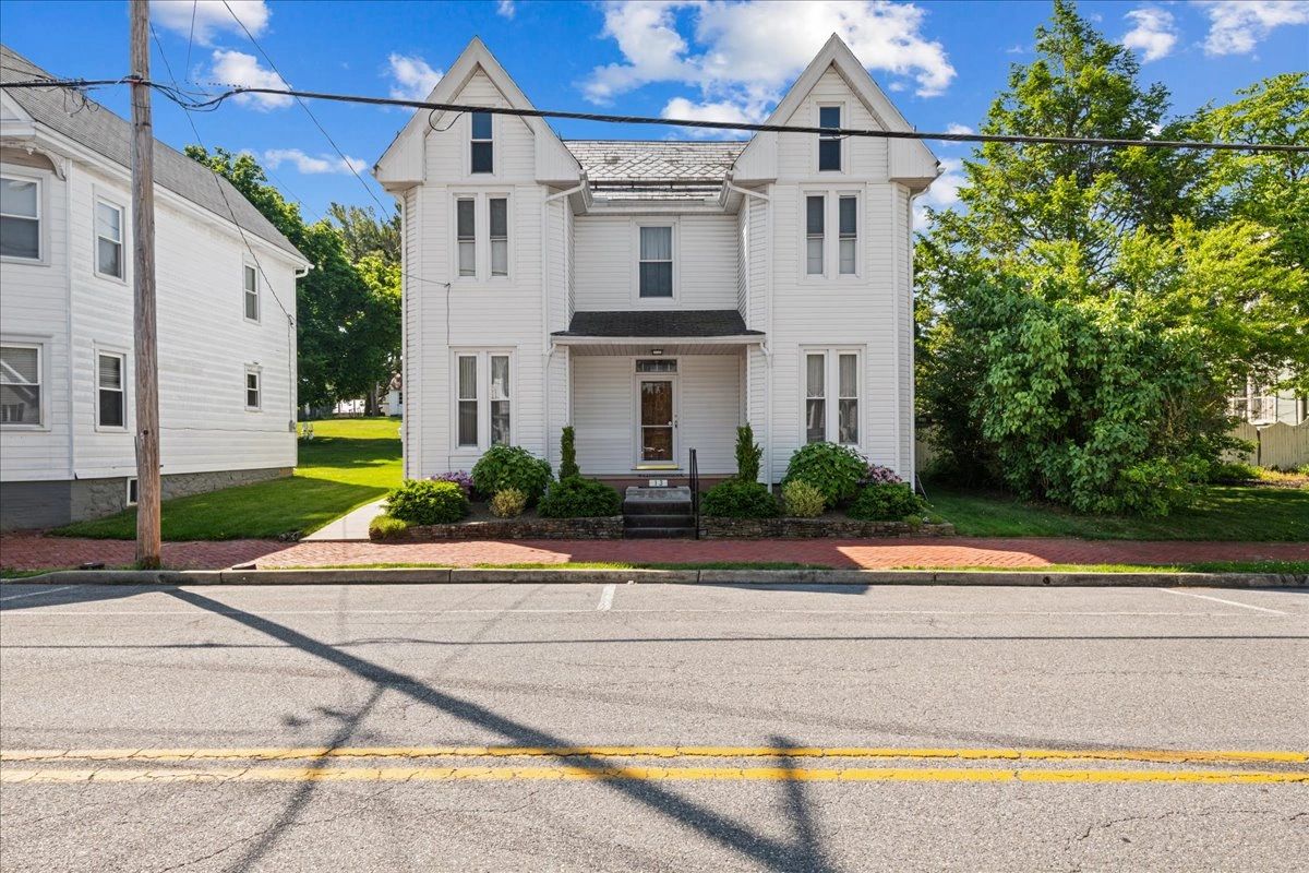 White two-story house with pointed roofs.