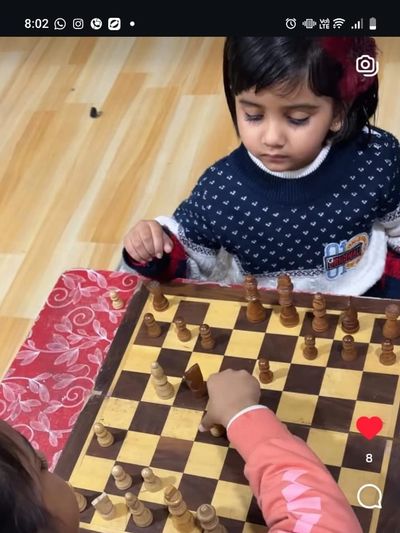 Two young children playing an intense game of chess indoors.