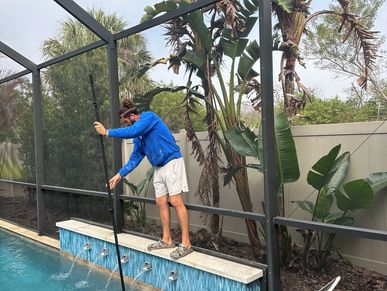 Man cleaning pool with pole.