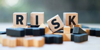 Wooden blocks spelling 'RISK' with one falling