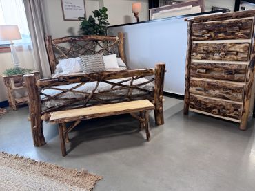 Rustic wooden bed, bench, and dresser in a cozy room.