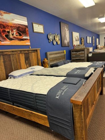 Wooden bed frames with mattresses displayed in a showroom.