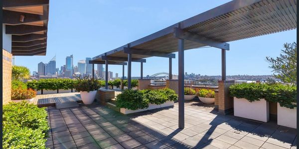 Modern rooftop terrace with plants and city skyline view.