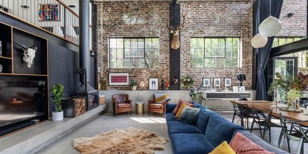 Spacious industrial living room with exposed brick walls and modern furnishings.