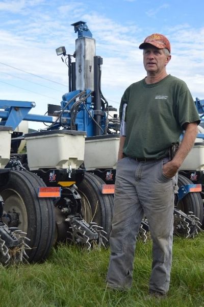 Man standing next to large agricultural machinery in a field.