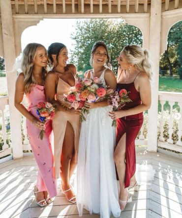 Bride with bridesmaids in colorful dresses holding bouquets.