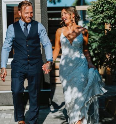 Happy couple holding hands, dressed for a formal occasion.