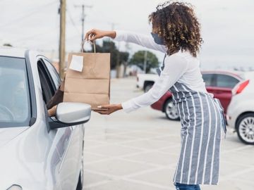 Lady handing over brown bag to driver. Roadside pickup service