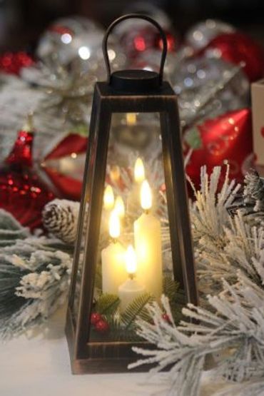 Christmas distressed lantern with lighted candles and greenery.