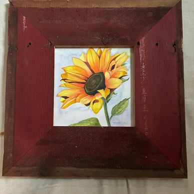 Framed painting of a sunflower with a rustic red frame.