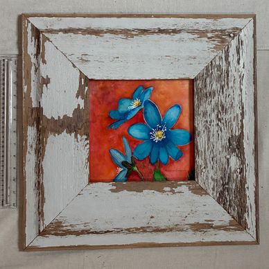 Blue flowers painted on an orange background in a rustic wooden frame.