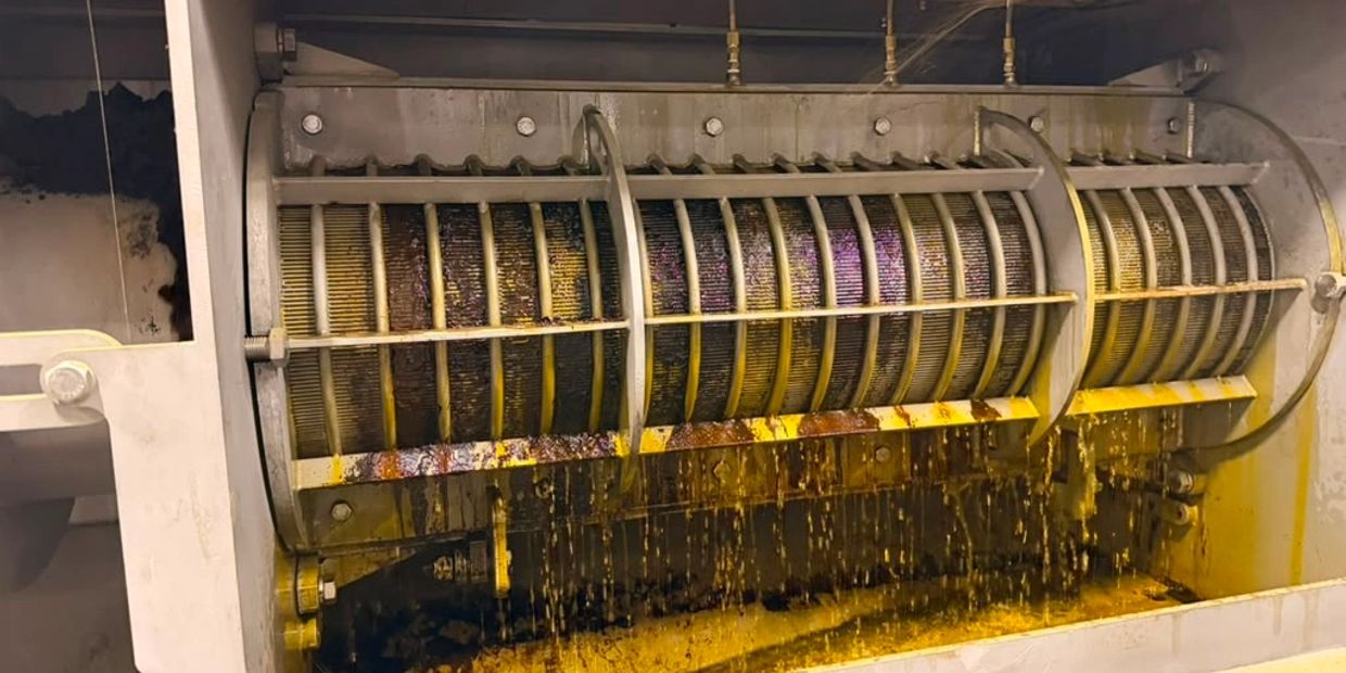 Industrial machine processing liquid with dripping yellow and brown substances.