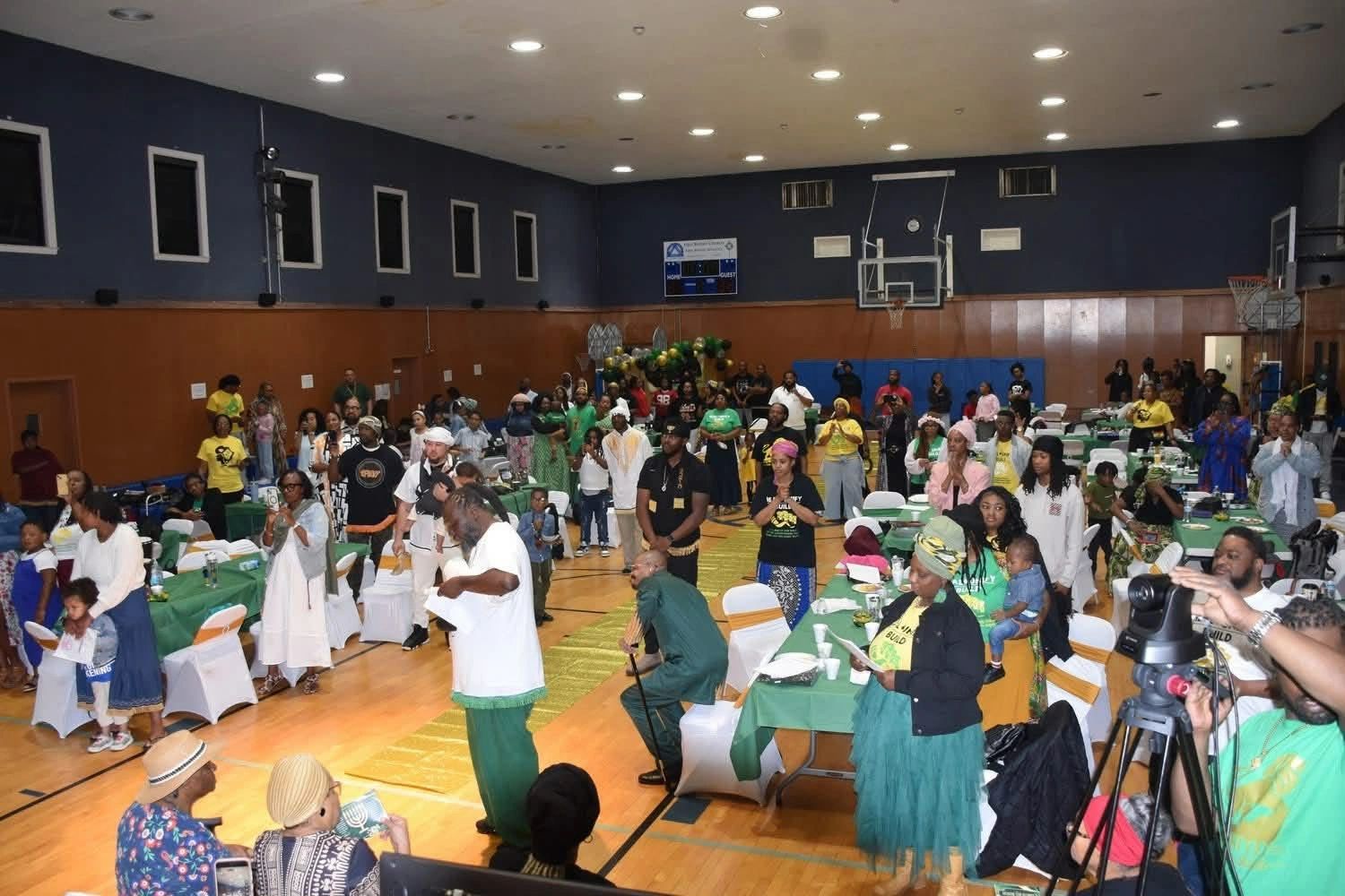 Community gathering in a decorated gymnasium with diverse attendees.