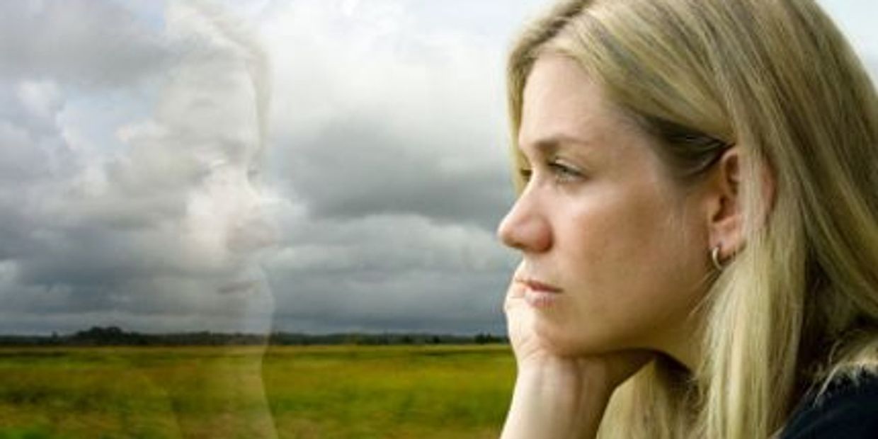 Blonde woman gazing into reflection out of window