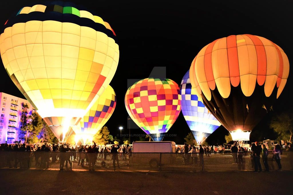 Nighttime hot air balloons glowing brightly with crowds watching.