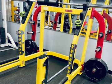 Yellow and red Smith machine in a gym.