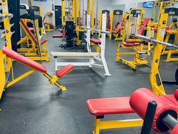 Empty gym with yellow and red workout machines.