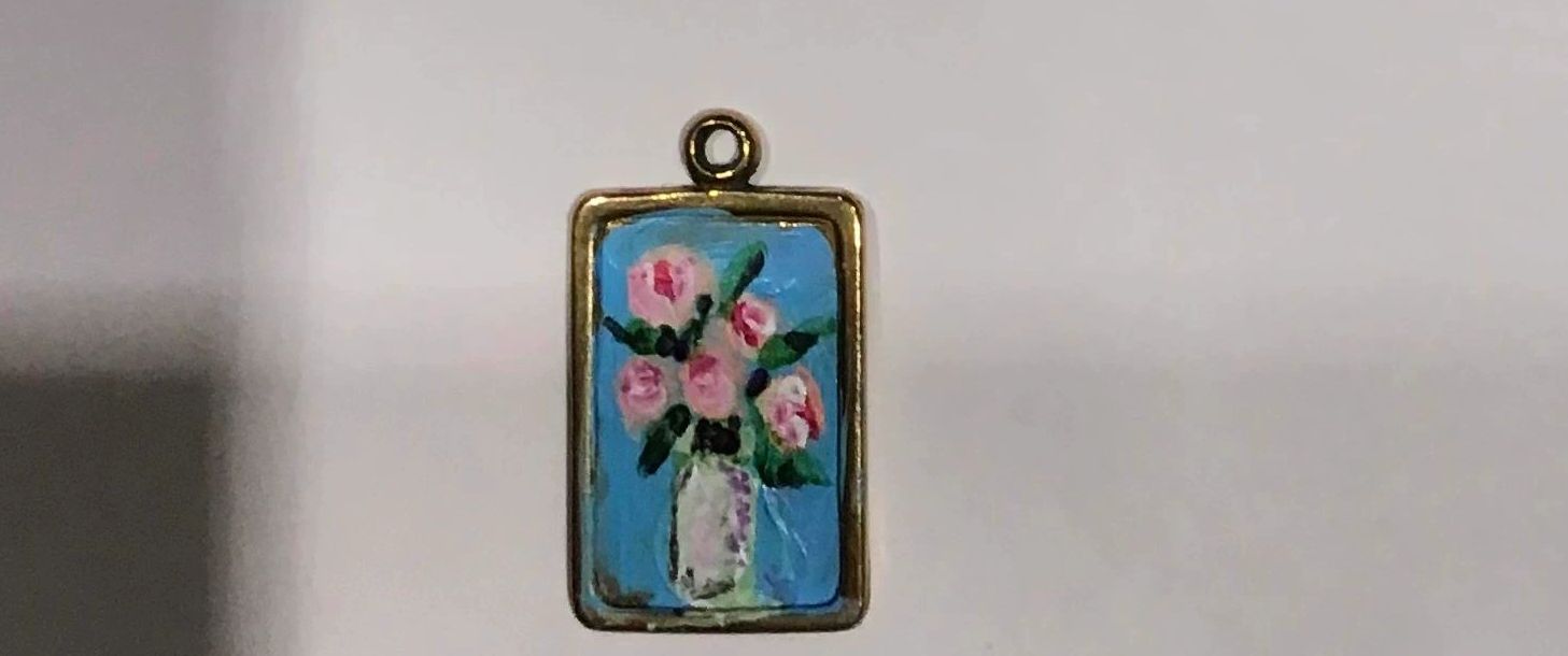 Earring charm or small necklace charm.  White vase of pink roses. Blue background.