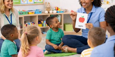 Teacher showing an apple flashcard to children in a classroom.