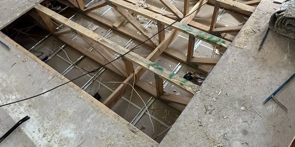Open floor with exposed wooden beams and wiring.