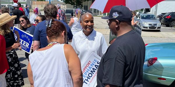 People gather outdoors for a political event supporting Sophie Thomas.
