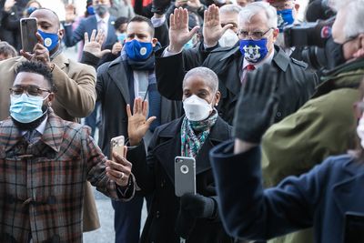 A group of masked people raising their hands in a public gathering.