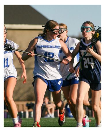 Girls playing lacrosse in a competitive game.