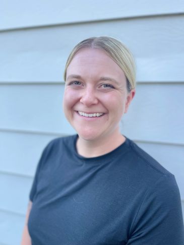 Smiling person with blonde hair in a black shirt.