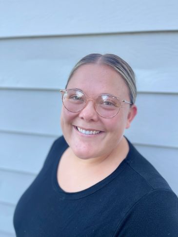 Smiling woman wearing glasses and a black shirt.