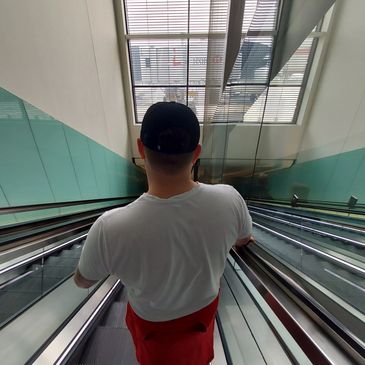 Person on an escalator descending indoors.