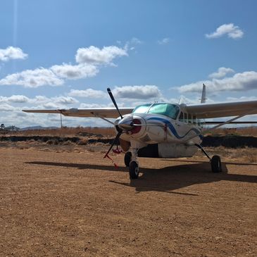Small single-engine airplane parked on dry dirt.