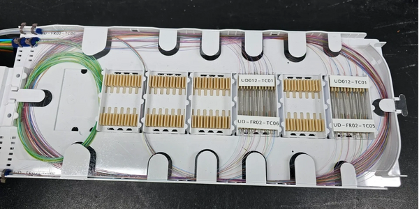 Organized fiber optic splice tray with labeled connectors and neatly arranged fibers.