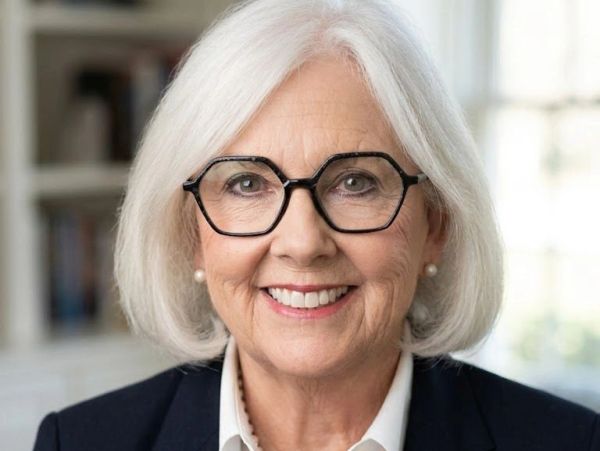 Smiling elderly woman with white hair and glasses.