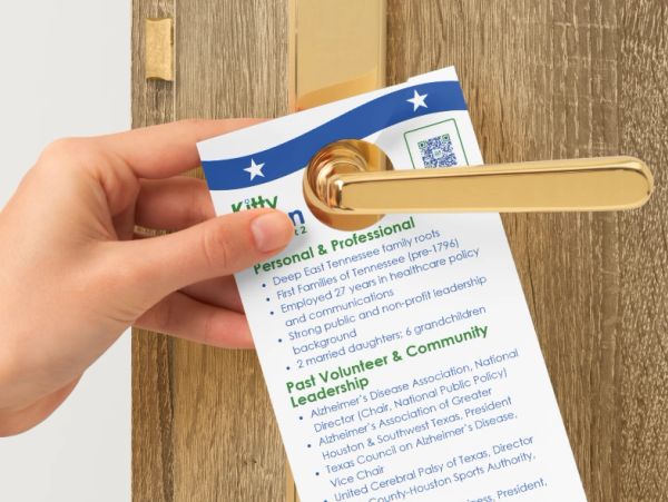 Hand placing a flyer on a gold door handle.