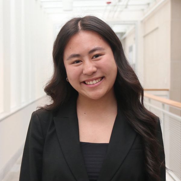 Smiling young woman with long dark hair in a black blazer.