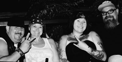Four friends smiling and posing, making peace signs in a black-and-white photo.