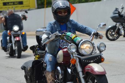Person riding a motorcycle wearing a helmet and sunglasses.