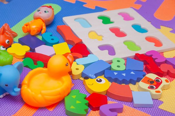 Colorful children's toys and puzzle pieces scattered on a play mat.