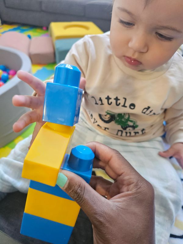A child intently watching colorful building blocks being stacked.