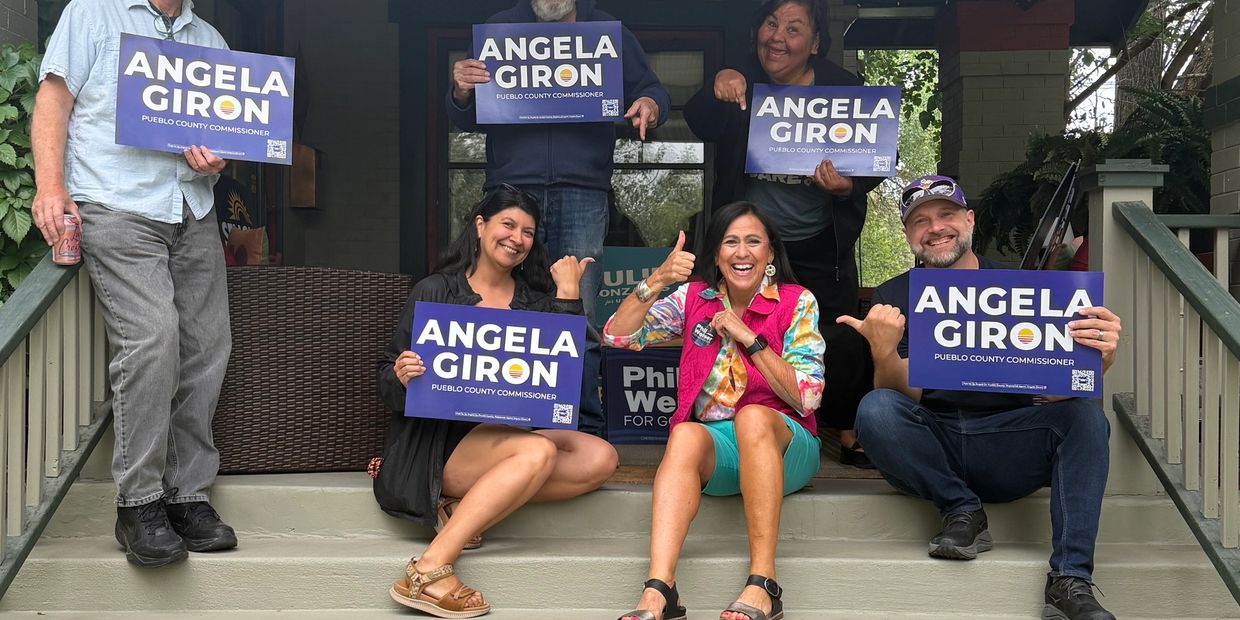 Group holding Angela Giron signs on porch steps.