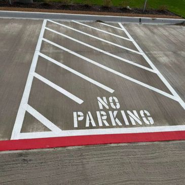A concrete no parking zone marked with white diagonal lines and text.