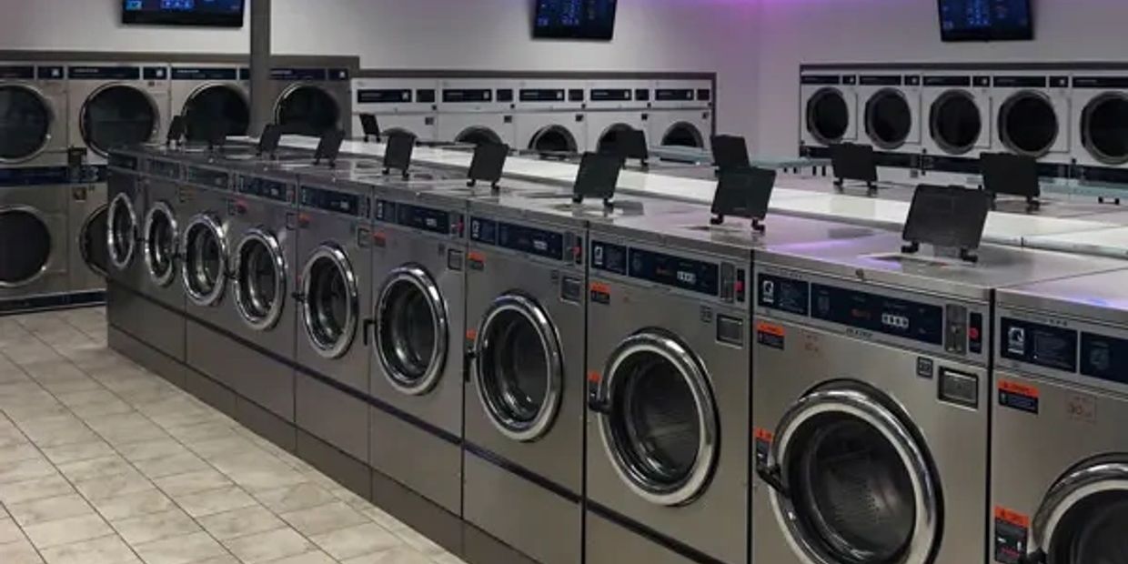 Row of industrial washing machines in a laundromat.