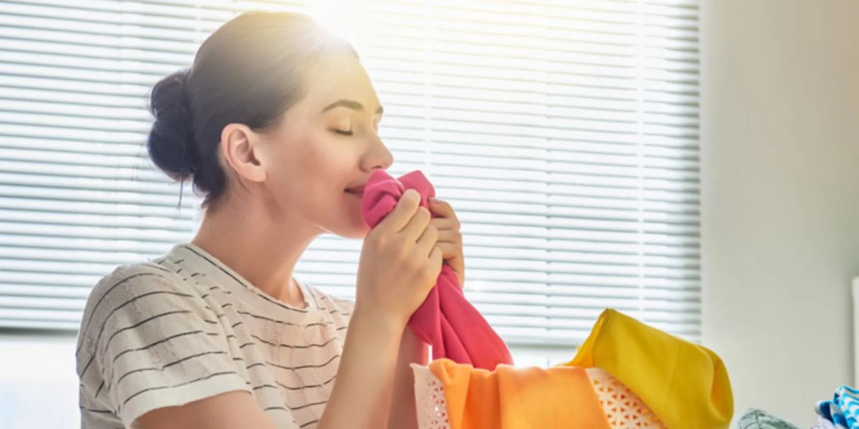 Woman happily smelling freshly washed clothes.
