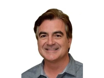 Smiling middle-aged man with brown hair in a gray shirt.
