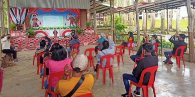 People attending a socially distanced event with red chairs.