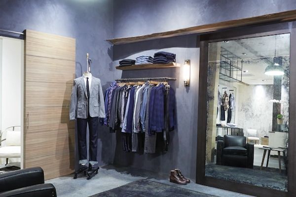 Modern boutique with men's clothing and leather chairs.