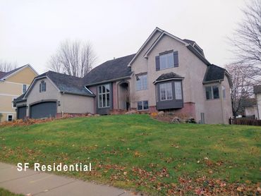 A large suburban home with a sloped lawn and attached garage.