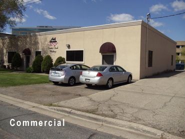 Commercial building with two parked cars and clear blue sky.