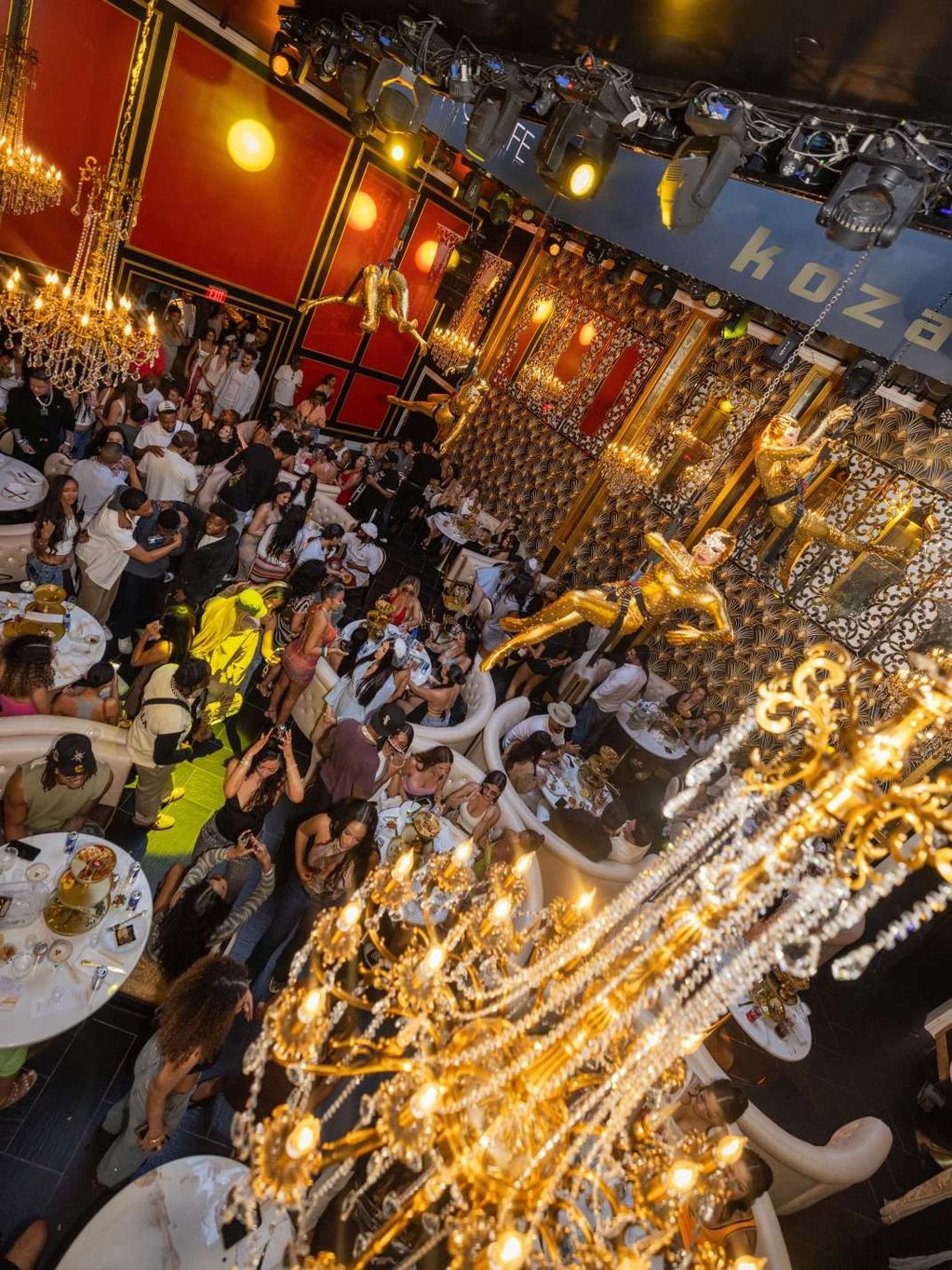 A lively nightclub scene with golden chandeliers and performers in gold costumes.