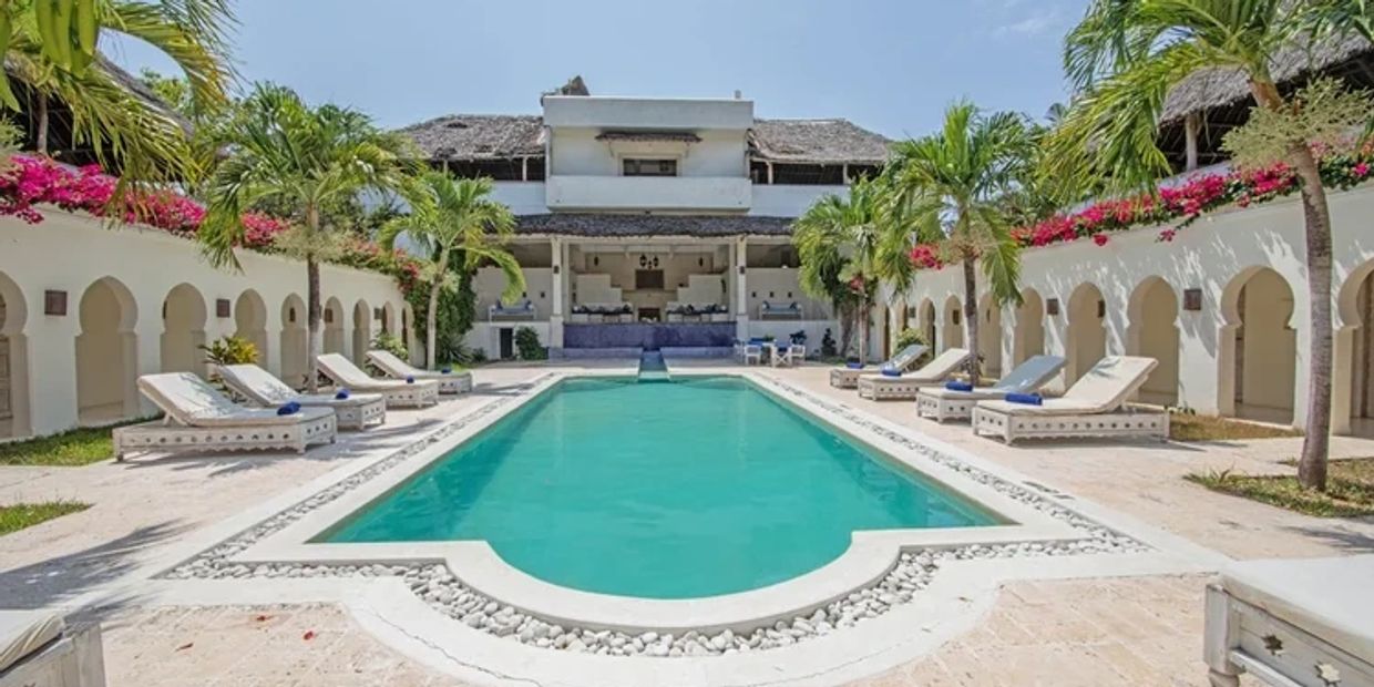 A serene pool surrounded by lounge chairs and tropical plants at a resort.